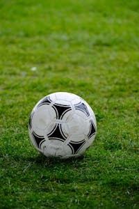 Close-up of a classic soccer ball resting on a lush green field.