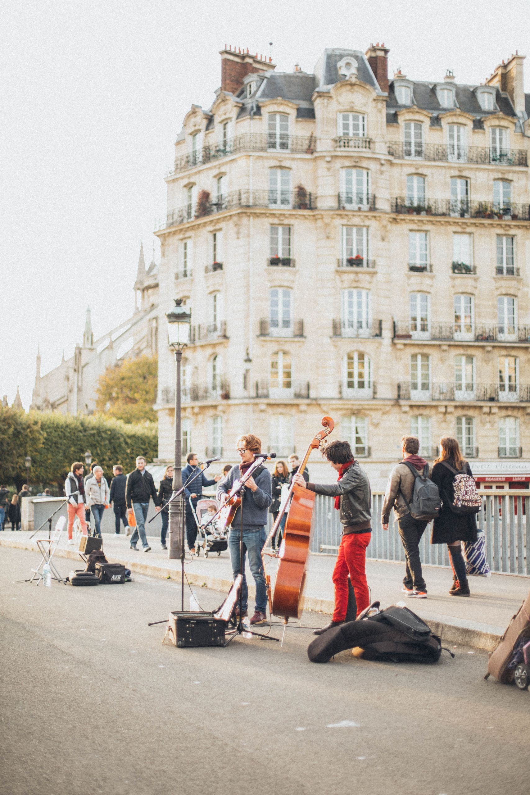 Vibrant street musicians performing near a historic building, attracting tourists and locals in an urban atmosphere.